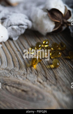 Softgels con olio di semi di cotone su una superficie di legno. Primo piano Foto Stock