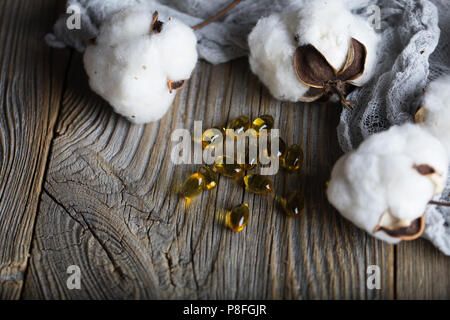 Softgels con olio di semi di cotone su una superficie di legno. Primo piano Foto Stock