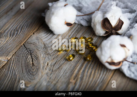 Softgels con olio di semi di cotone su una superficie di legno. Primo piano Foto Stock