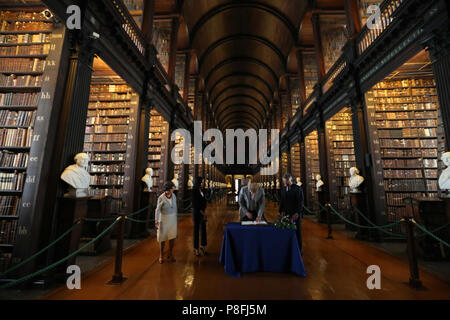 Il Duca e la Duchessa di Sussex firmare il libro degli ospiti, guardato dalla Trinità, Provost e Presidente, Dr Patrick Prendergast e bibliotecario del collegio, Helen Shenton nella sala lunga della vecchia libreria come parte della loro visita al Trinity College di Dublino. Foto Stock