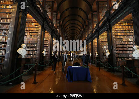 Il Duca e la Duchessa di Sussex firmare il libro degli ospiti, guardato dalla Trinità, Provost e Presidente, Dr Patrick Prendergast in sala lunga della vecchia libreria come parte della loro visita al Trinity College di Dublino. Foto Stock