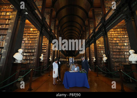 Il Duca e la Duchessa di Sussex firmare il libro degli ospiti, guardato dalla Trinità, Provost e Presidente, Dr Patrick Prendergast e bibliotecario del collegio, Helen Shenton nella sala lunga della vecchia libreria come parte della loro visita al Trinity College di Dublino. Foto Stock