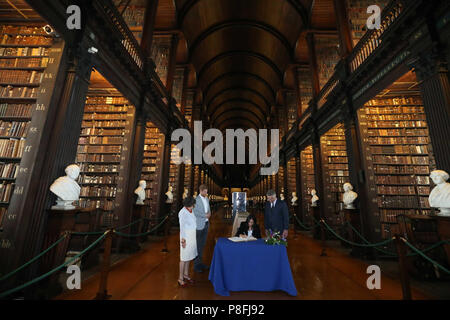 Il Duca e la Duchessa di Sussex firmare il libro degli ospiti, guardato dalla Trinità, Provost e Presidente, Dr Patrick Prendergast e bibliotecario del collegio, Helen Shenton nella sala lunga della vecchia libreria come parte della loro visita al Trinity College di Dublino. Foto Stock