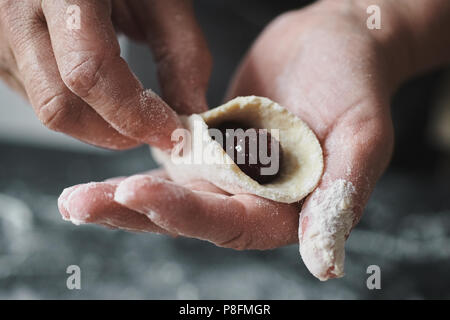 Donna cook scolpisce manualmente ravioli ripieni con ciliegie Foto Stock