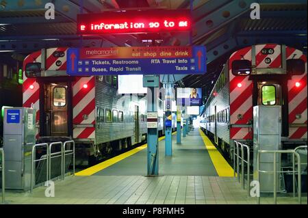 Chicago, Illinois, Stati Uniti d'America. Coppia di Metra treni pendolari attendono i passeggeri e un orario di partenza al Obilivie Centro per il trasporto. Foto Stock