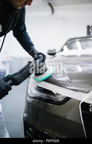 Dettagli auto - Lavoratore con lucidatrice orbitale nel negozio di riparazioni auto. Foto Stock