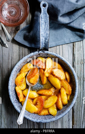 Pesche cotte in una padella su un sfondo di legno Foto Stock