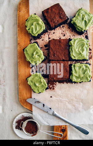 Brownie di Avocado, alcuni dei quali sono sormontate con glassa di avocado e che per il resto sono conditi con polvere di cacao fotografato su carta da forno da t Foto Stock