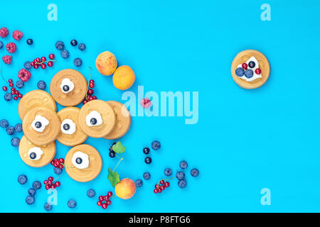 Delizioso sorriso mini pancake con bacche blu sulla superficie, vista dall'alto. Appartamento laico, vista dall'alto cibo dolce sfondo. Foto Stock