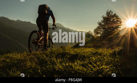 Un uomo biker sulla sua bike Mountain bike al Tramonto nelle Dolomiti le montagne delle Alpi Italia Foto Stock