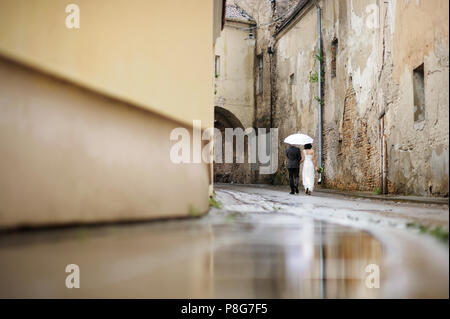 Sposa e lo sposo a piedi sotto un ombrello Foto Stock