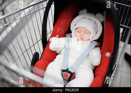 Ragazza neonata nel sedile auto in un carrello della spesa Foto Stock