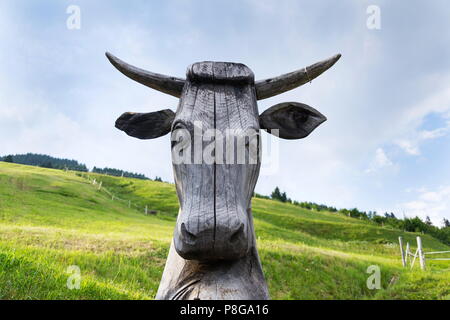 Vacca in legno statua di testa con splendide Alpi verdi pascoli di montagna Foto Stock