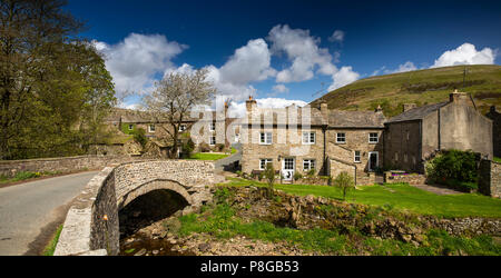 Regno Unito, Inghilterra, Yorkshire, Swaledale, Thwaite, case di villaggio attraverso ponte sopra la paglia Beck, panoramica Foto Stock