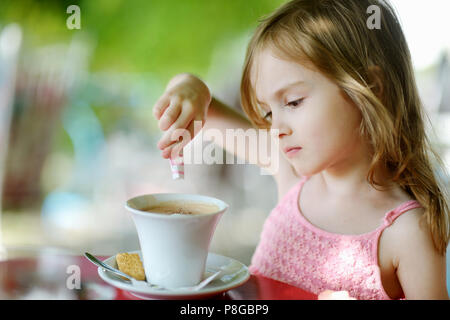 Adorabile ragazza versando lo zucchero nel cioccolato caldo Foto Stock