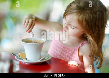 Adorabile ragazza versando lo zucchero nel cioccolato caldo Foto Stock