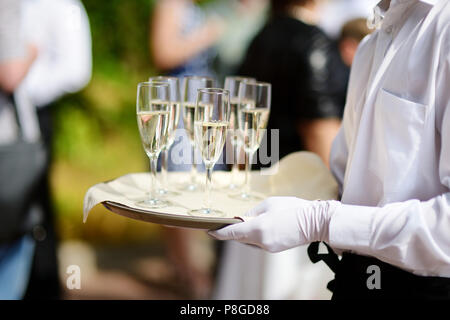 Cameriere con piatto di champagne e bicchieri di vino Foto Stock