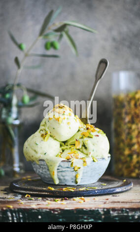 Ciotola di pistacchio gelato con pistacchio verde dadi sulla cucina in legno contatore, close-up. Estate rinfrescante gelato deserto Foto Stock