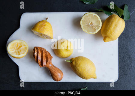 I limoni con centrifuga in legno sul bordo di marmo Foto Stock