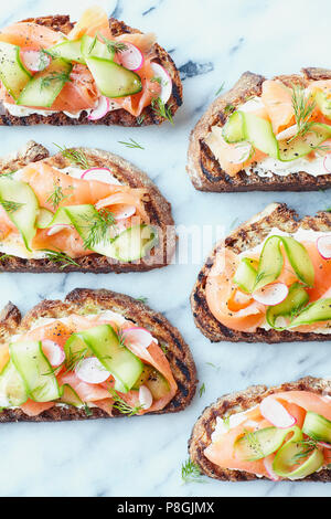 Salmone affumicato e cetrioli sandwiches aperti su marmo Foto Stock