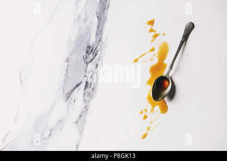 In casa liquido trasparente marrone zucchero caramellato in cucchiaio vintage su marmo bianco dello sfondo. Appartamento laico, spazio. Foto Stock