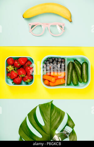 Creative laici piatto con gli occhiali, pranzo sano e foglia di monstera sui colori pastello sullo sfondo Foto Stock