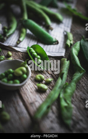 I piselli in un baccello e gren fagioli n un rustico tavolo da cucina Foto Stock