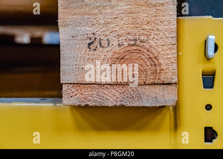 Vista ravvicinata e poco profonda di un pallet di stoccaggio in legno visto seduto su un ripiano di magazzino in metallo. Mostra i dettagli della trave in legno tagliata. Foto Stock