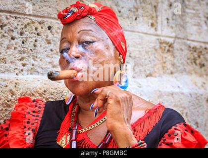 Donna cubana di fumare un sigaro, in abito tradizionale, guarda la fotocamera, ritratto, Havana, Cuba Foto Stock