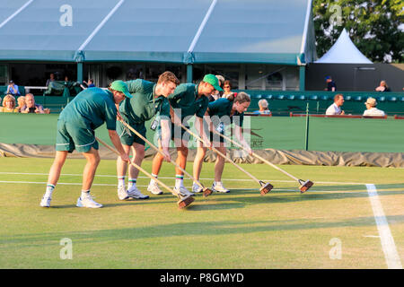 Corte assistenti di manutenzione strisciare una erba di Wimbledon corte per preservare il prato Foto Stock