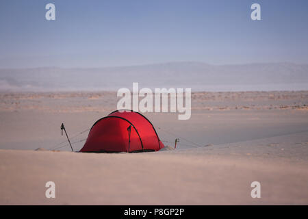 Tenda Rossa su di una vasta apertura campo di sabbia con le dune tutti intorno in un deserto. Foto Stock