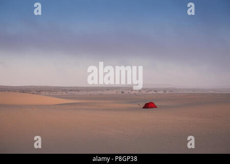 Tenda Rossa su di una vasta apertura campo di sabbia con le dune tutti intorno in un deserto. Foto Stock