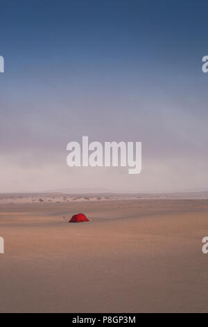 Tenda Rossa su di una vasta apertura campo di sabbia con le dune tutti intorno in un deserto. Foto Stock