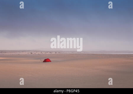 Tenda Rossa su di una vasta apertura campo di sabbia con le dune tutti intorno in un deserto. Foto Stock