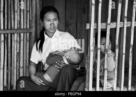 Una donna della tribù AKHA infermieri un bambino in bamboo house - villaggio nei pressi di Kengtung o KYAINGTONG - Myanmar Foto Stock