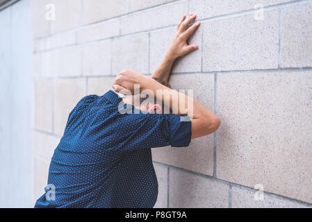 Teen punzonatura di un muro di mattoni di frustrazione. Foto Stock