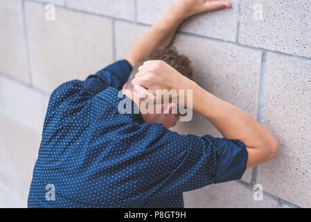 Teen punzonatura di un muro di mattoni di frustrazione. Foto Stock