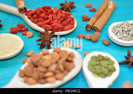 Concetto di tabella con semi aromatiche e frutta in cucchiai di legno su sfondo blu, closeup, il fuoco selettivo Foto Stock