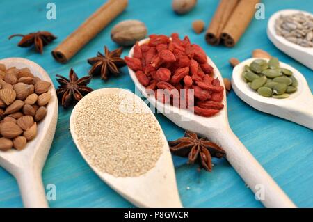 Concetto di tabella con semi aromatiche e frutta in cucchiai di legno su sfondo blu, closeup, il fuoco selettivo Foto Stock