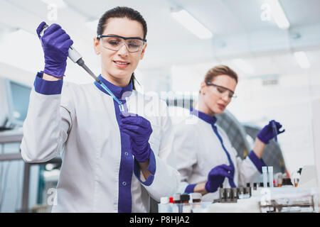 Lieta persona di sesso femminile che lavorano in laboratorio scientifico Foto Stock
