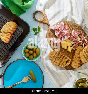 Tavolo pranzo concetto. Vista superiore snack italiani Bruschetta blu sul tavolo di legno, vista dall'alto. Foto Stock