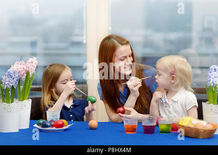 Giovane madre e le sue due figlie di pittura delle uova di Pasqua Foto Stock