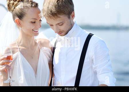 Felice sposa e lo sposo di bere champagne su uno yacht Foto Stock