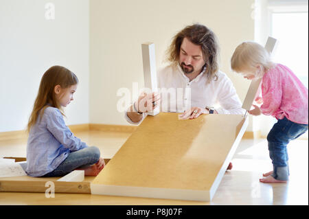Padre Felice e le sue due figlie assemblando una tabella insieme Foto Stock