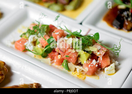 Insalata estiva stagionale composta da cocomero, avocado, formaggio rasato, olio, erbe e spezie Foto Stock