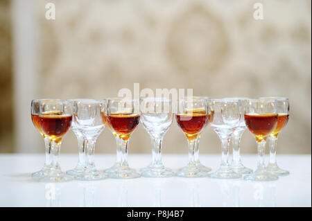 Bicchieri di brandy disposti in una fila sul tavolo bianco Foto Stock