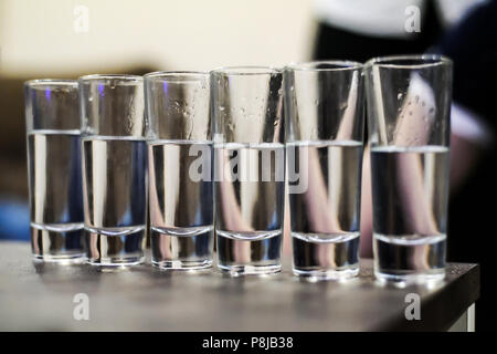 Alcool trasparente scatti bicchieri in una riga Foto Stock