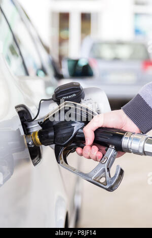 Primo piano della mano mans pompando benzina in auto alla stazione di gas. Foto Stock