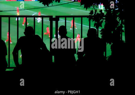 Silhouette naturale di tifosi di spettatori guardando la partita di calcio sul grande schermo sulla piazza della città Foto Stock