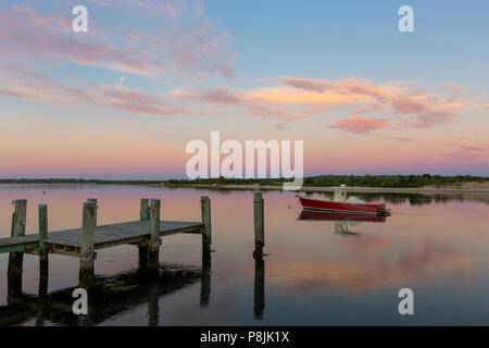 Un lone rosso barca ormeggiata su Menemsha Creek sotto un colorato pre-sunrise sky in Chilmark, Massachusetts di Martha's Vineyard. Foto Stock